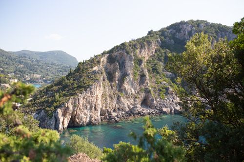 Free Breathtaking view of a rugged, green coastline with crystal clear waters on a sunny day. Stock Photo