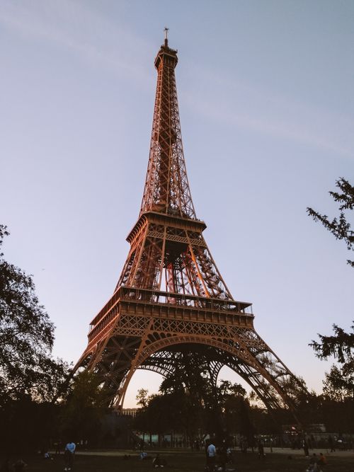 Free Capture of the Eiffel Tower at dusk, showcasing its iconic architecture from a low-angle view. Stock Photo