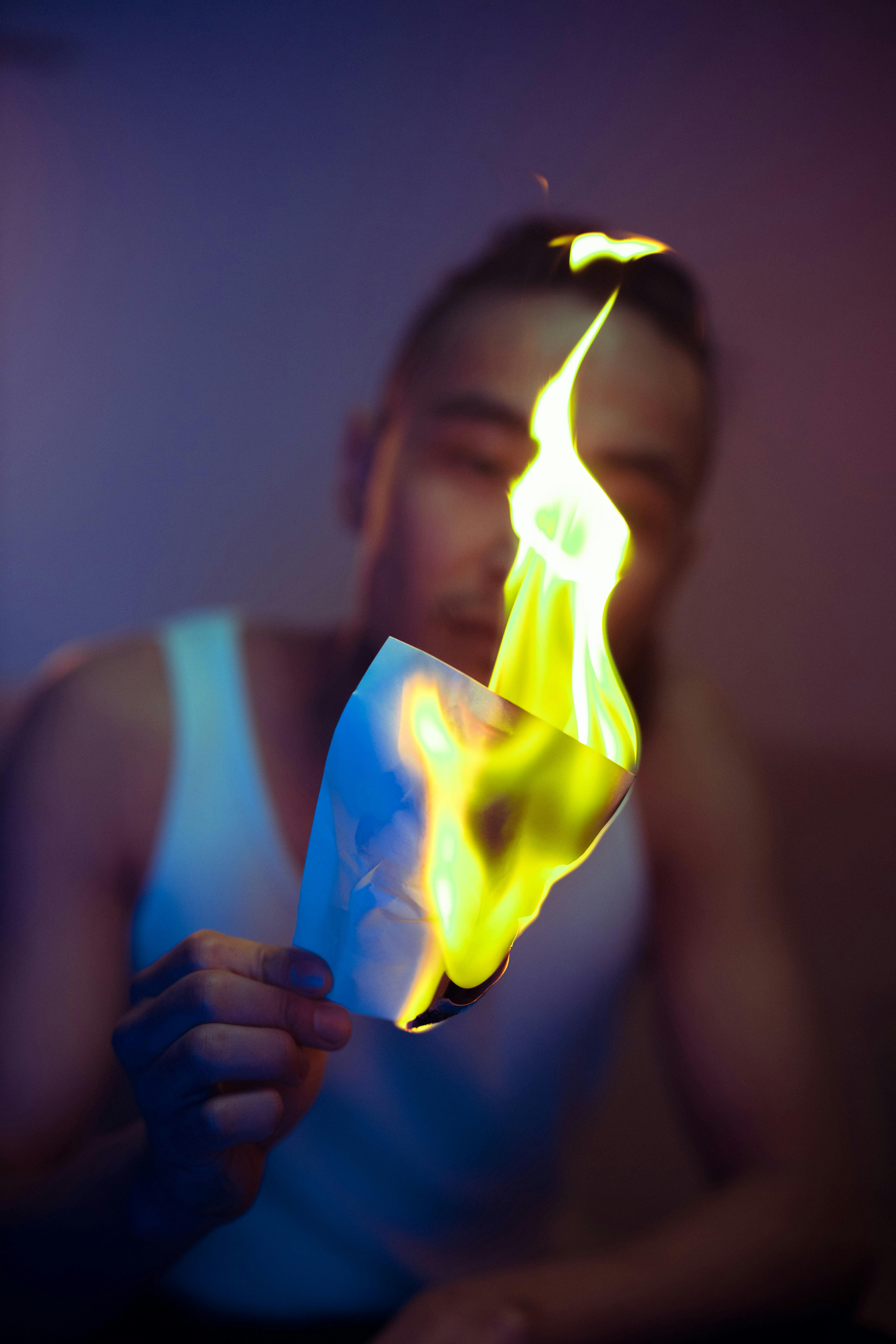 close up shot of a man holding a burning paper