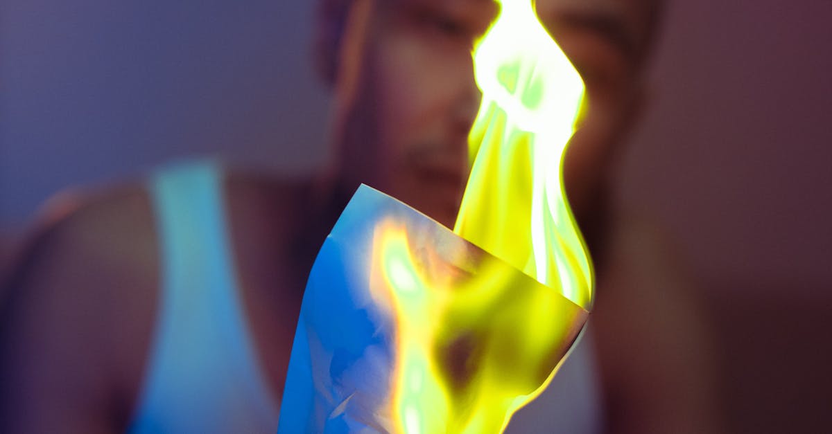An artistic shot of a man holding a burning paper with flames in focus, conveying intensity and drama.