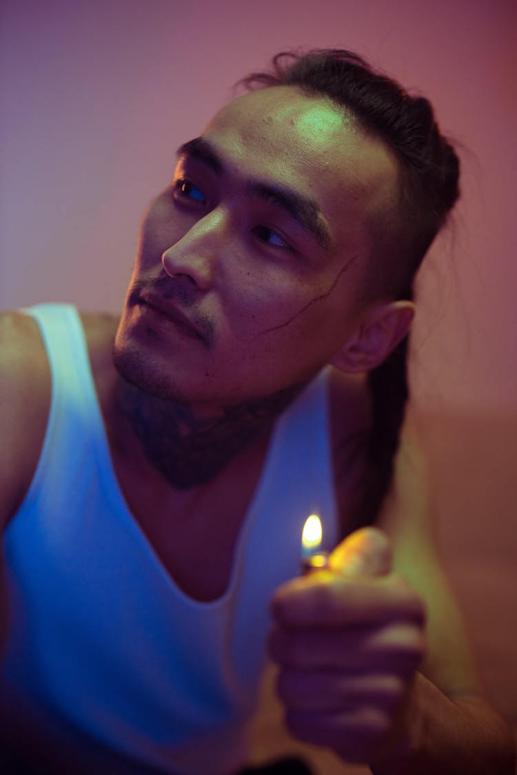 A Man In White Tank Top Holding A Lighter