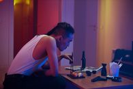 Man in White Tank Top Sitting on Table While Holding Black Chopsticks