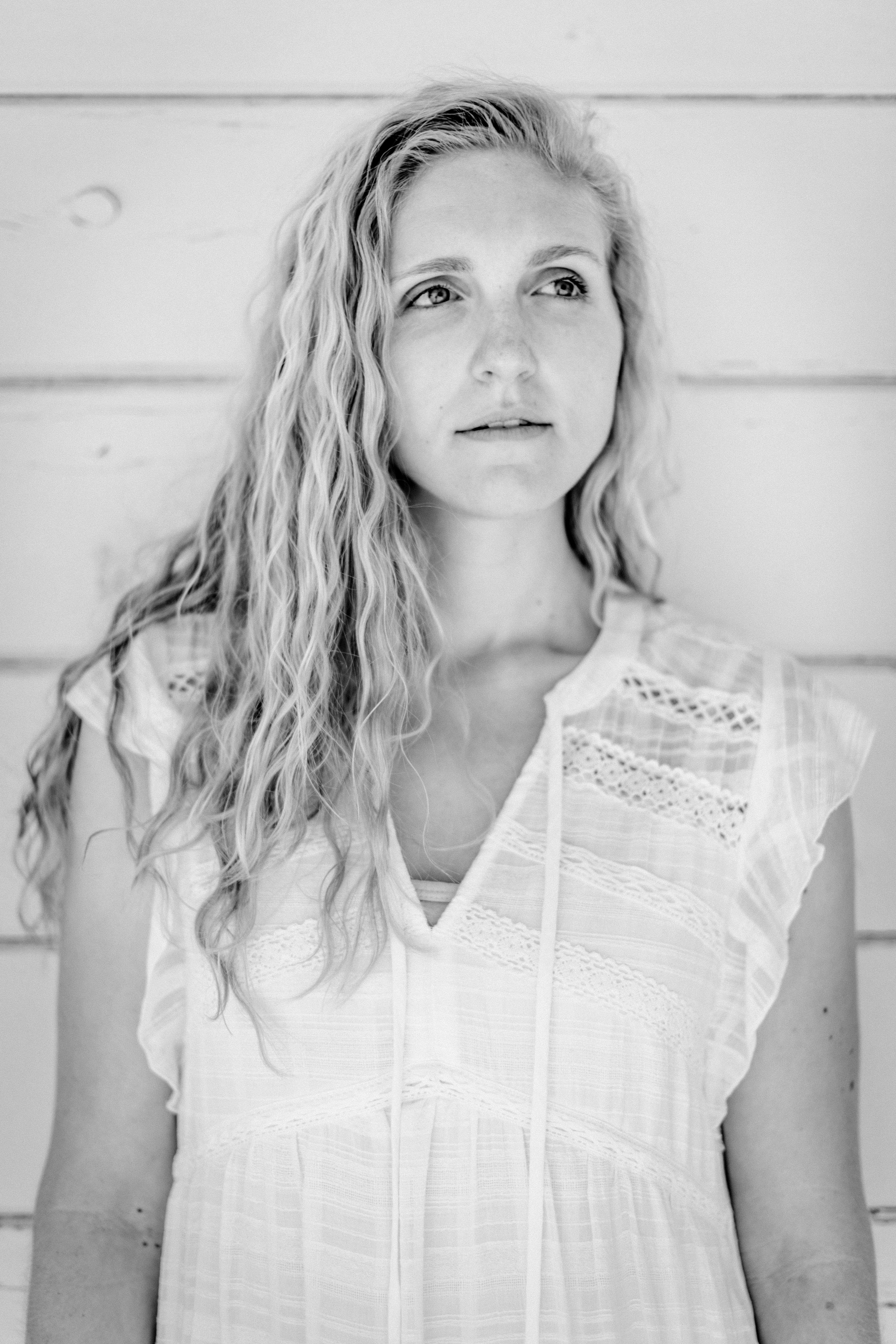 A black-and-white portrait of a woman with curly hair looking away thoughtfully.