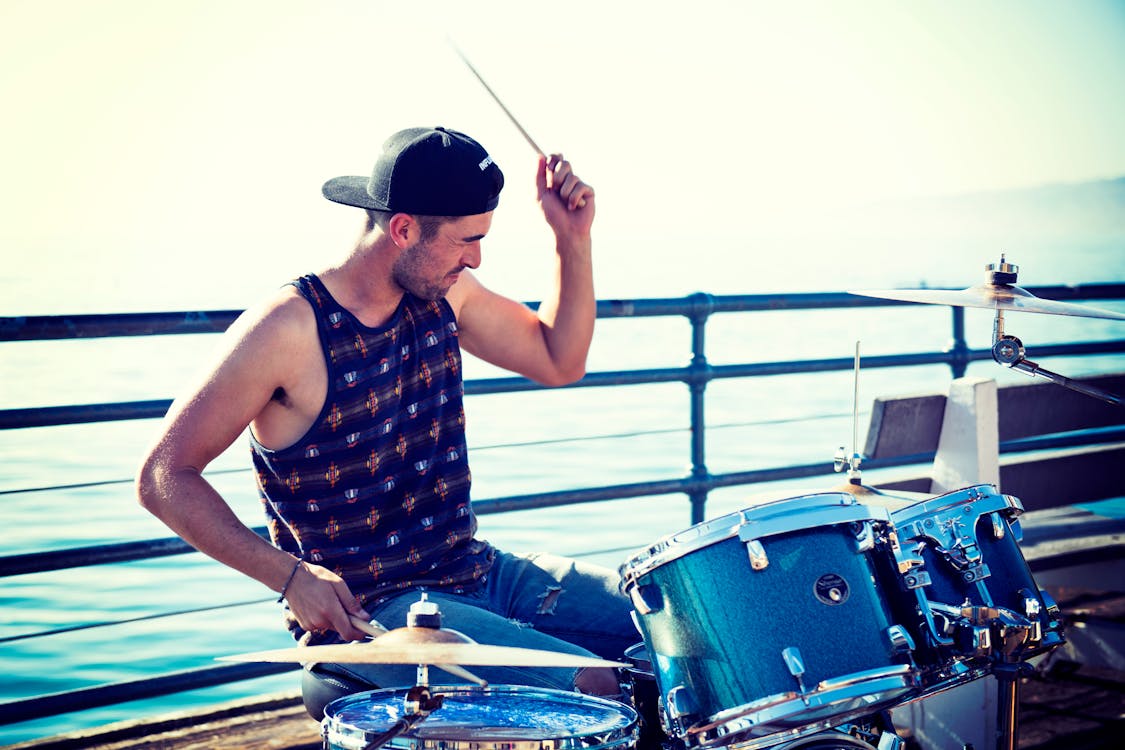 Free Man Playing Drum Near Bay at Day Time Stock Photo