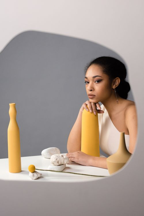 Free Contemporary portrait of a woman sitting among minimalist ceramic vases in a studio setting. Stock Photo