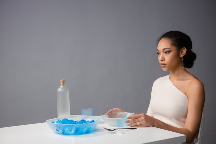 Woman In White Top Sitting By The Table