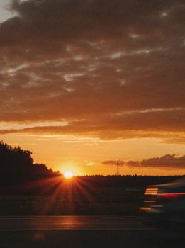 Captivating sunset over a road with motion blur of a passing vehicle. Perfect for nature or travel themes.