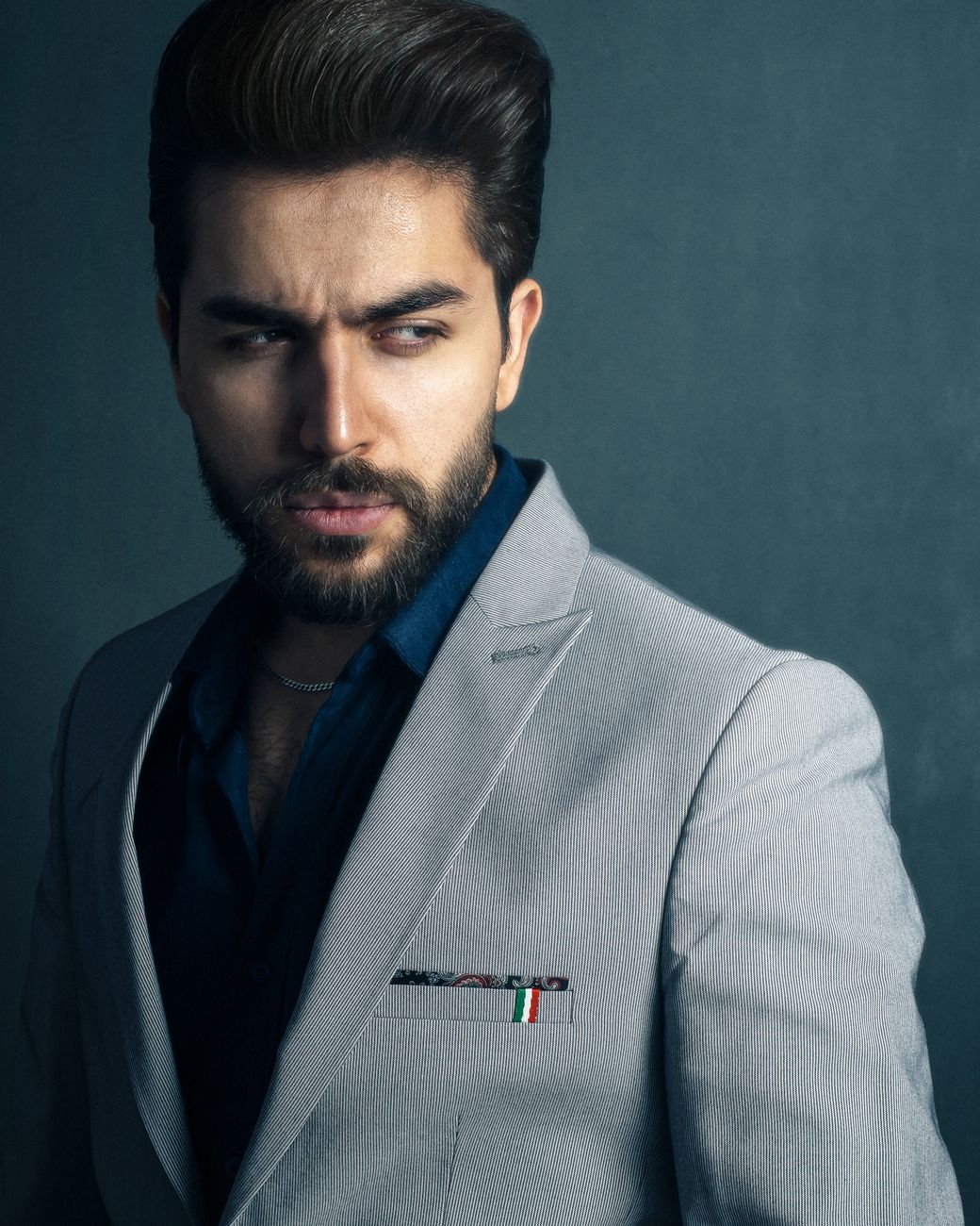Bearded man in a suit jacket posing confidently indoors.
