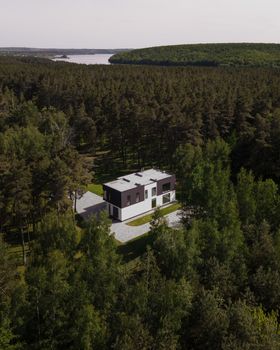 Aerial view of a modern house nestled within a dense forest in Solomino, Russia.