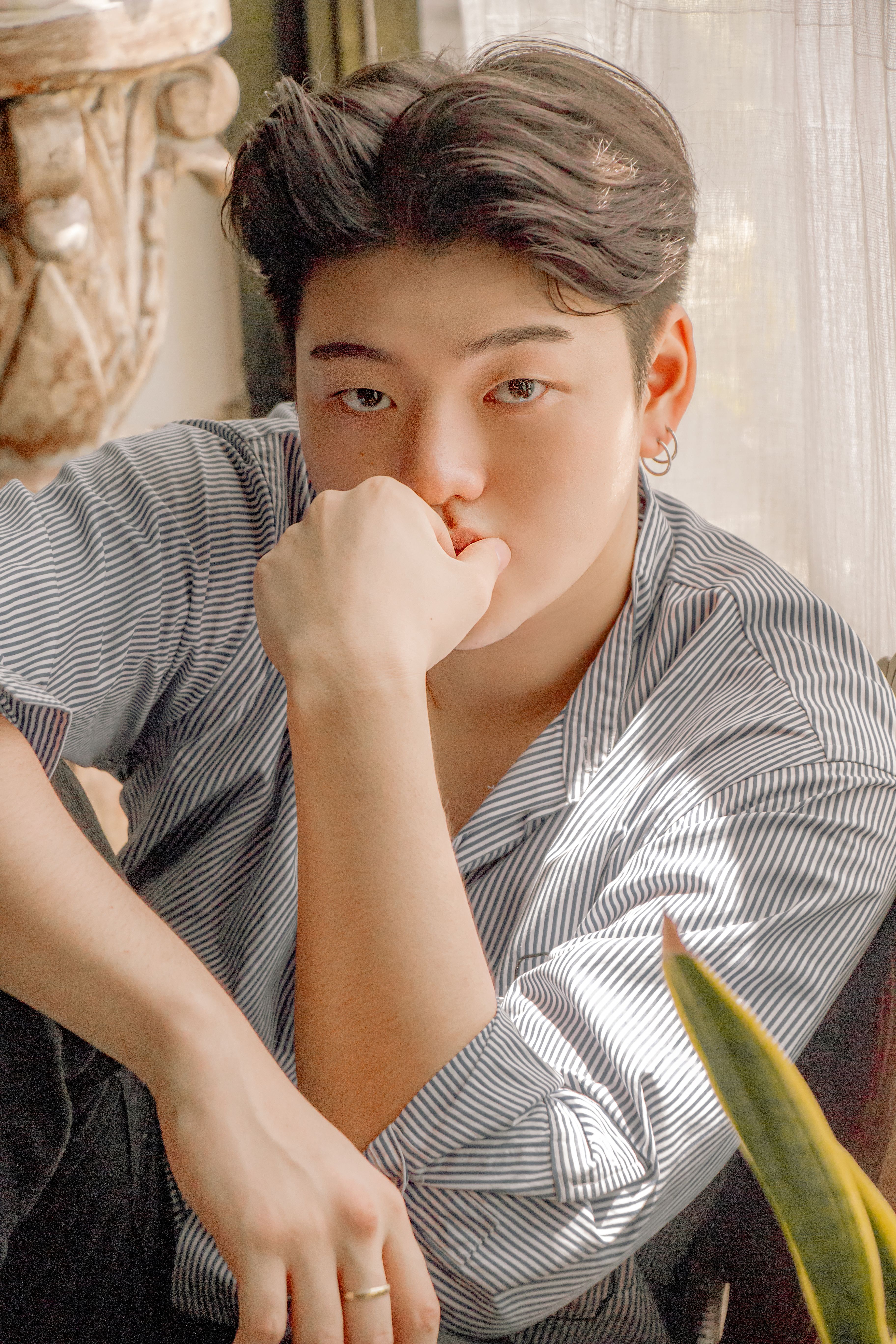 Handsome man posing indoors with a thoughtful expression wearing a striped shirt.