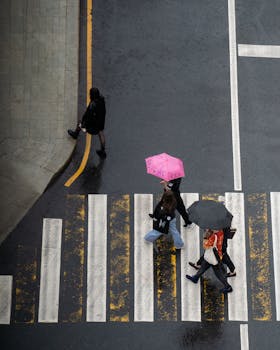 High-angle view of pedestrians with umbrellas crossing a rain-soaked intersection in Moscow.