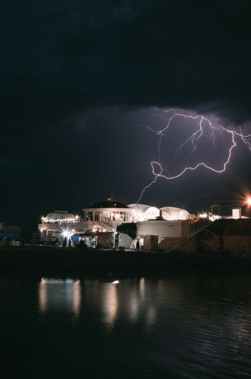 Free Dramatic lightning illuminates a grand seaside mansion during a powerful storm at night. Stock Photo