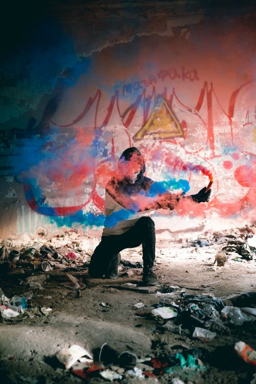 Free Graffiti artist creates vibrant scene with blue and red smoke in abandoned building. Stock Photo