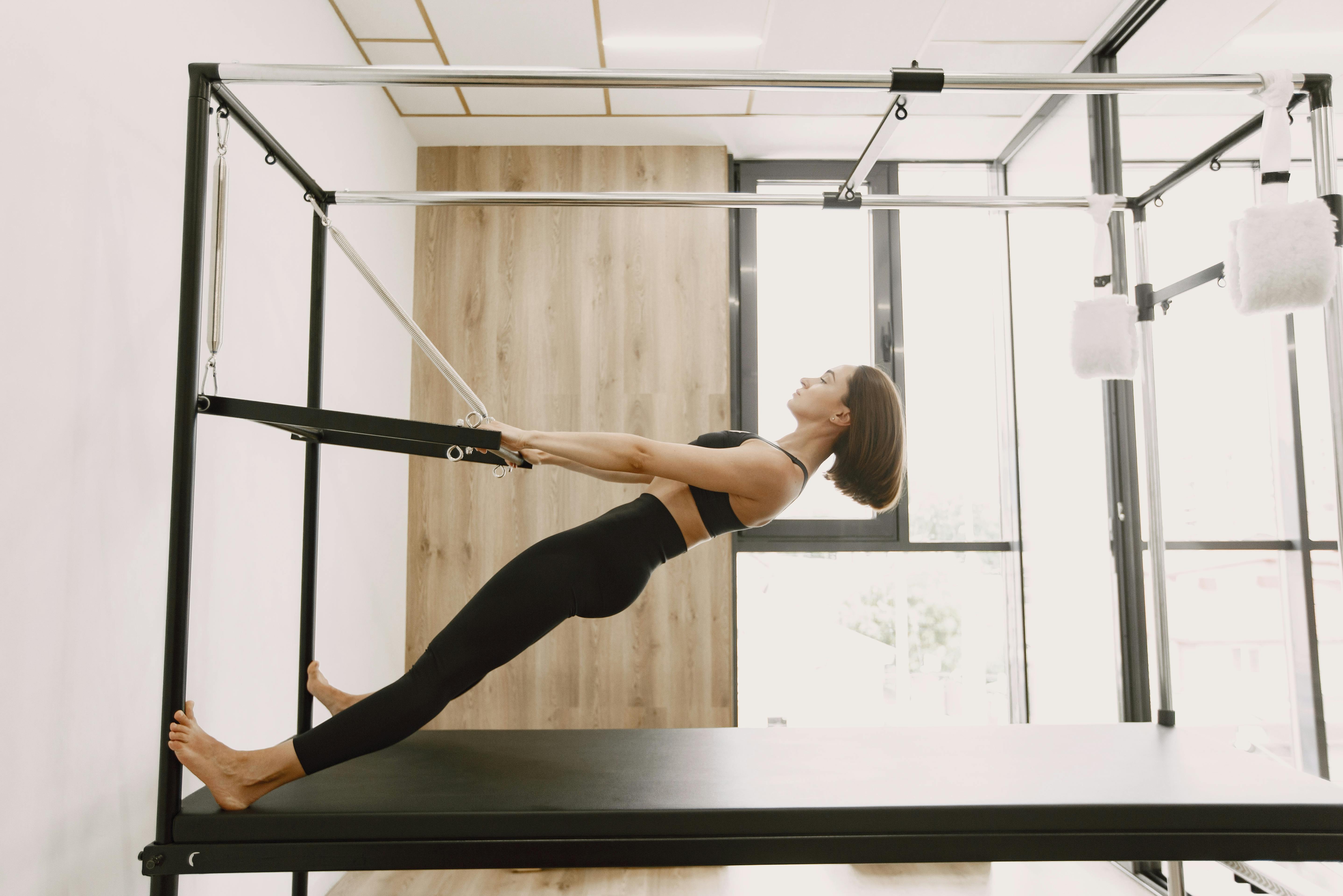 Free Woman performing fitness routine on Pilates machine in a modern gym setting. Stock Photo