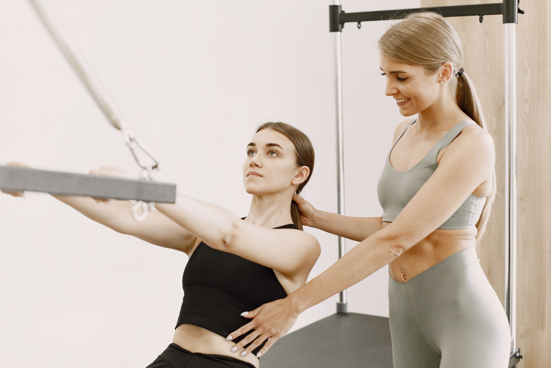 Personal trainer helping a client with fitness equipment in a gym setting.