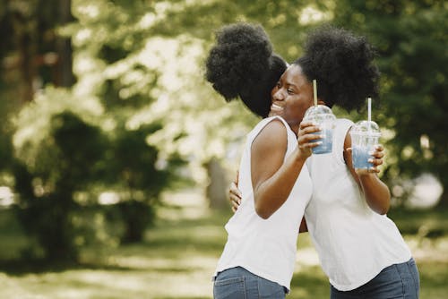 Free Women Holding Plastic Cup While Hugging Stock Photo