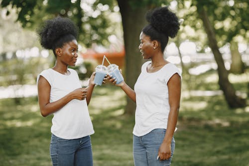 Women in White Tops Holding a Clear Plastic Cups with Drinks