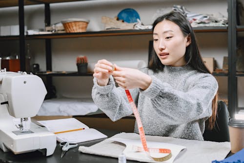 Woman Wearing a Gray Sweater Holding a Tape Measure