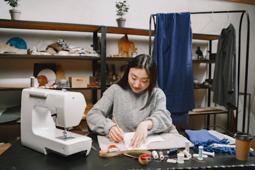 A Woman in Gray Sweater Making Patterns in a Fabric