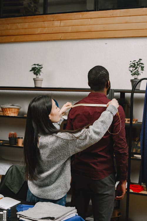 Woman Measuring A Man's Shoulder Length