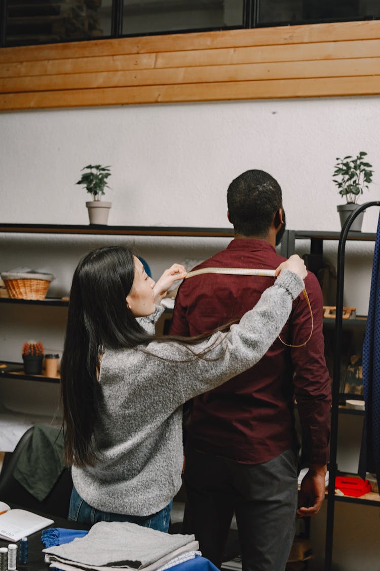 Woman Measuring A Man's Shoulder Length