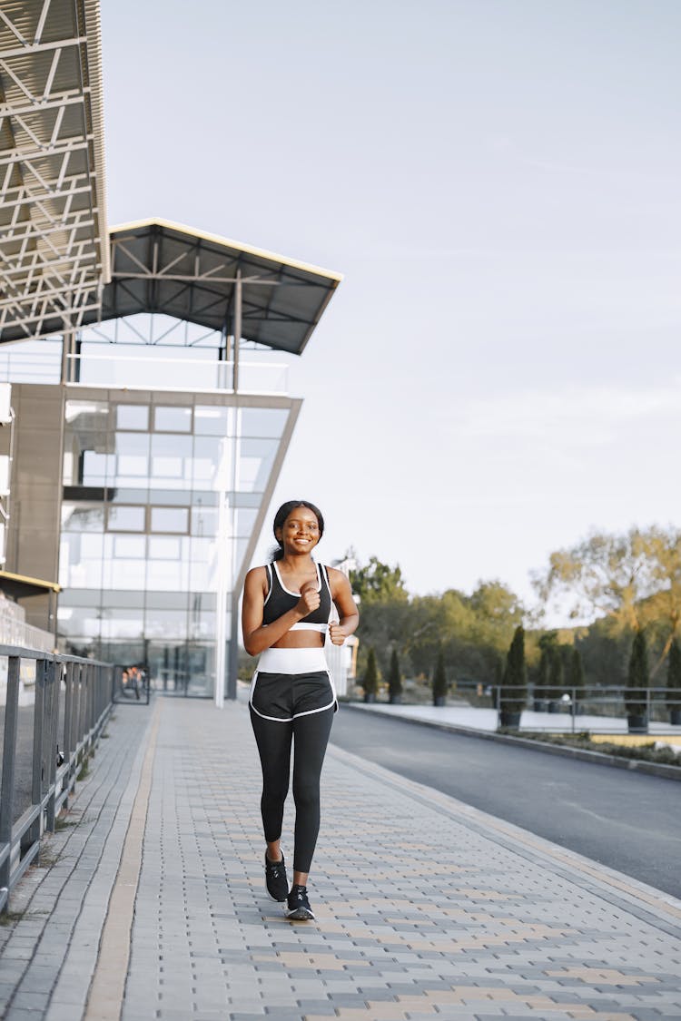 A Happy Woman Jogging On A Sidewalk During The Day