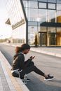Woman Sitting at a Gutter Using a Cellphone