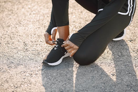 Close-up of a person tying black sports shoes on a sunny day, outdoors.
