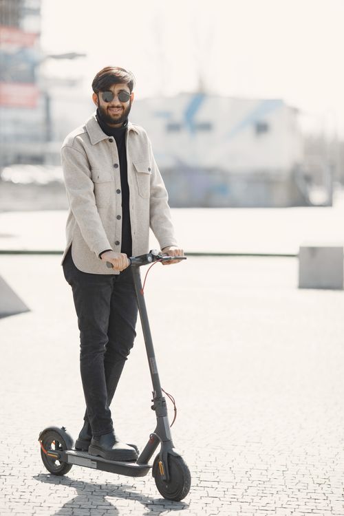 Free Man riding an electric scooter in an urban setting, stylish and modern. Stock Photo