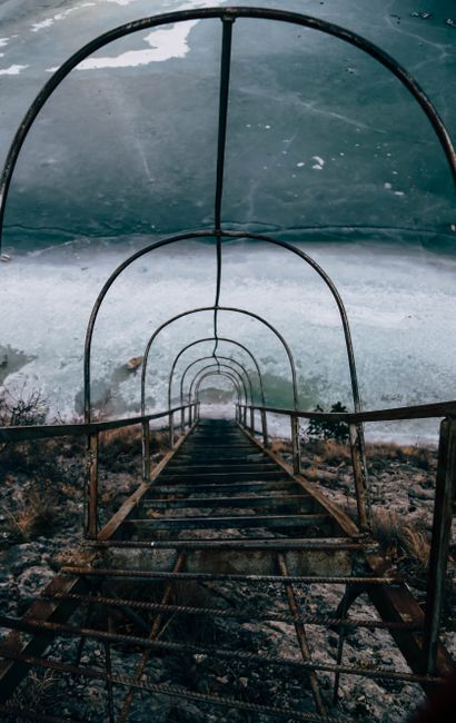 A dramatic view of a rusty metal staircase descending a cliffside by the sea in Dagestan, Russia.
