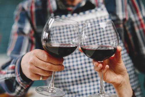 Close-up of two people clinking glasses of wine, celebrating indoors.