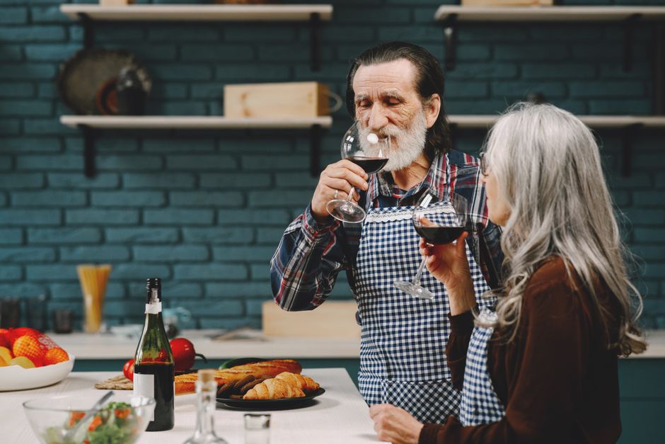 Photo by Gustavo Fring on Pexels Senior couple savoring red wine in their cozy kitchen with a relaxed atmosphere.