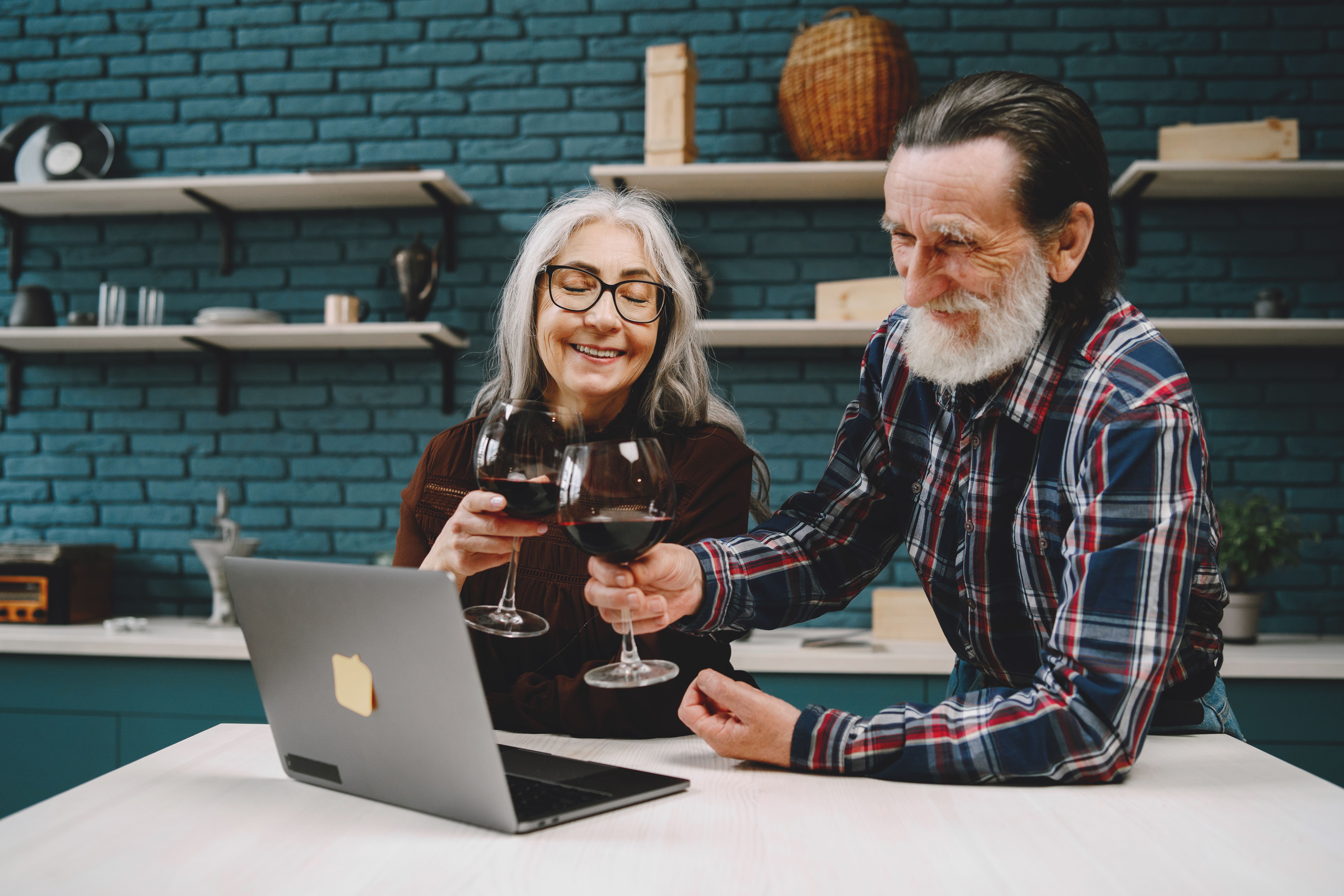 happy retiree couple reviewing finances on laptop with coffee