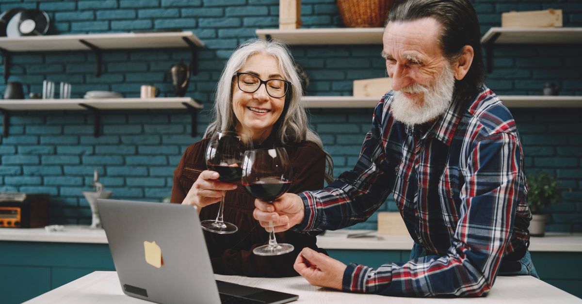 happy retiree couple reviewing finances on laptop with coffee