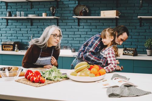 Free Warm family moment in a modern kitchen with fresh fruits and vegetables, embracing and laughter. Stock Photo