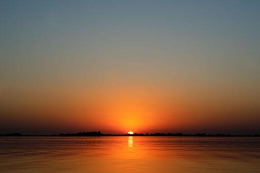 A serene sunset over a calm ocean with a peaceful horizon and vivid colors.
