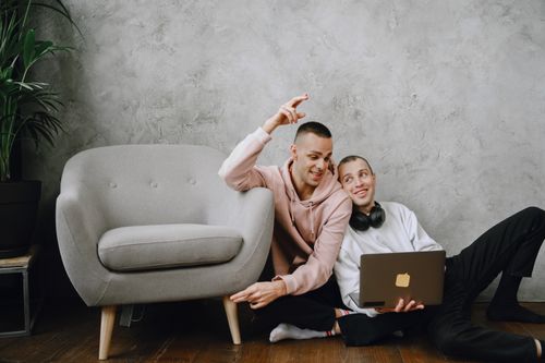 Free A joyful couple sitting on the floor, using a laptop, symbolizing love and relaxation. Stock Photo