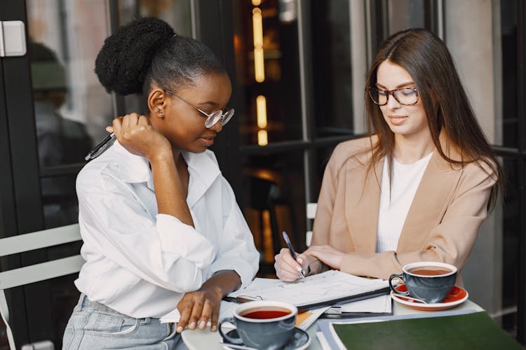 Women Reviewing Documents While Having Tea