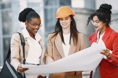 Free Three diverse women professionals examining blueprints in an urban setting. Stock Photo