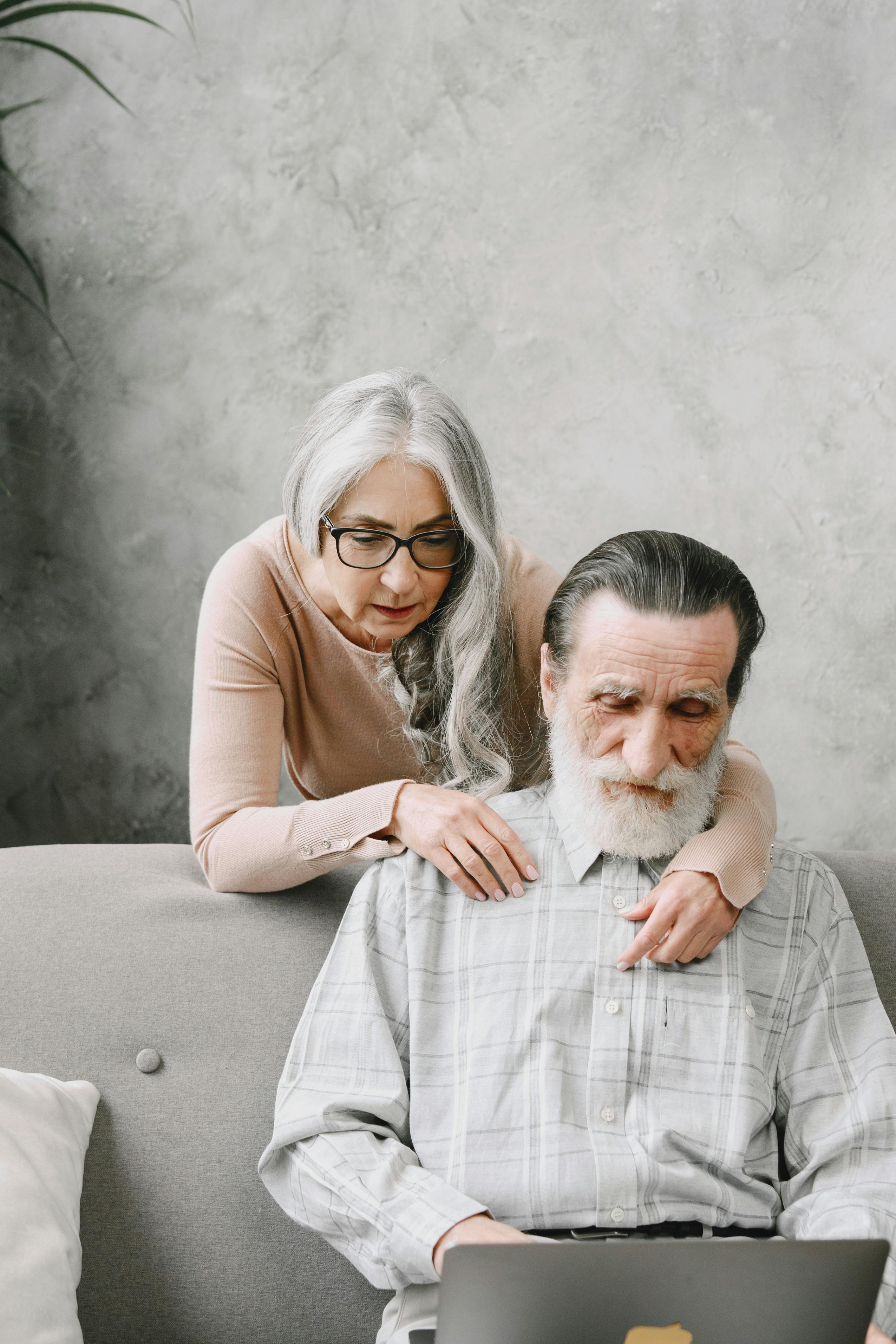 Elderly couple exploring technology on a cozy couch at home.