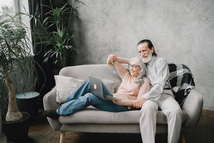 Happy Elderly Couple Sitting On A Sofa 