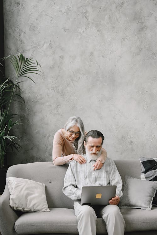 Man and Woman Looking at Laptop While on Sofa