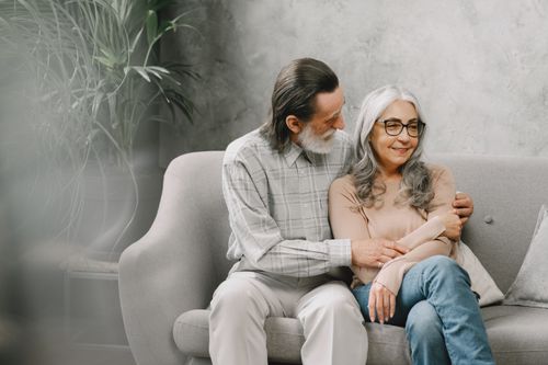 Free Happy senior couple embracing on a cozy sofa at home, enjoying togetherness. Stock Photo