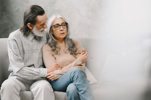 Free Elderly couple sitting closely, expressing comfort and support in a cozy living room setting. Stock Photo