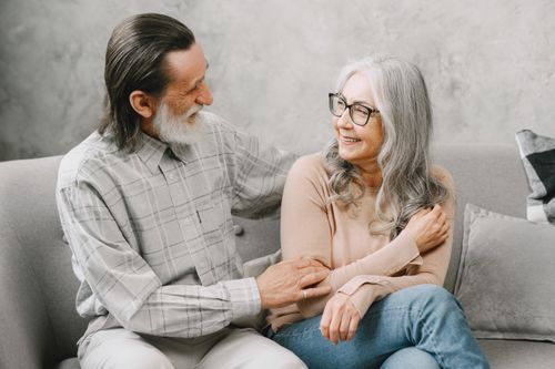 Free Charming elderly couple sharing a warm embrace while sitting indoors on a cozy sofa. Stock Photo