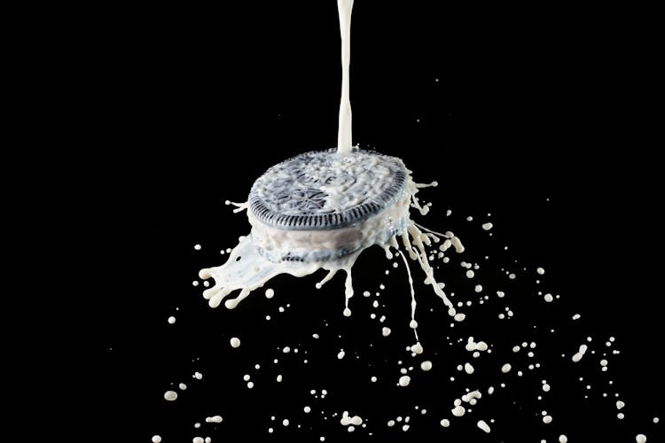 Pouring Milk On Chocolate Cookie With Vanilla Filling