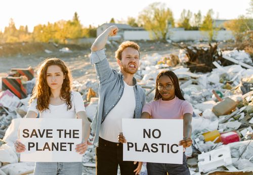 Free Group of activists holding signs against plastic pollution at a dumpsite, urging to save the planet. Stock Photo