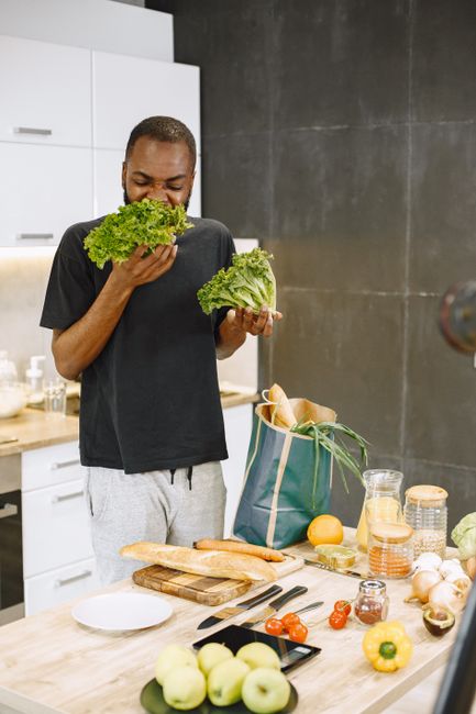 African American man enjoying fresh lettuce in a modern kitchen setting. African American man enjoying fresh lettuce in a modern kitchen setting.