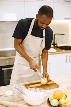 A man slicing an apple in a modern kitchen, focusing on food preparation.