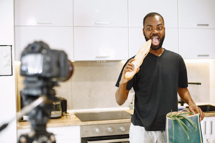 Male Vlogger Eating A Baguette In A Video Shoot